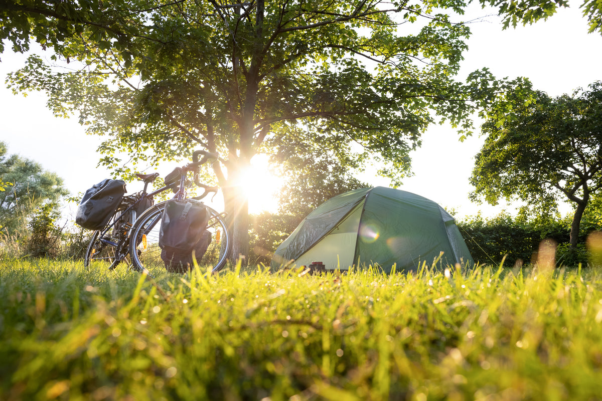 A tent set up next to a bicycle with panniers.