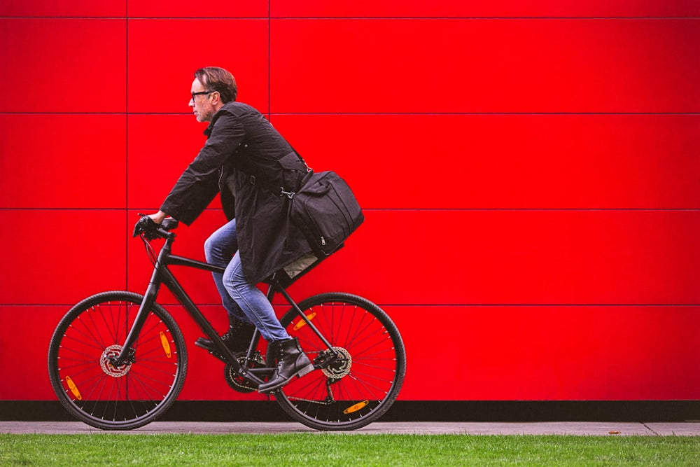 person riding a bike in front of a red wall