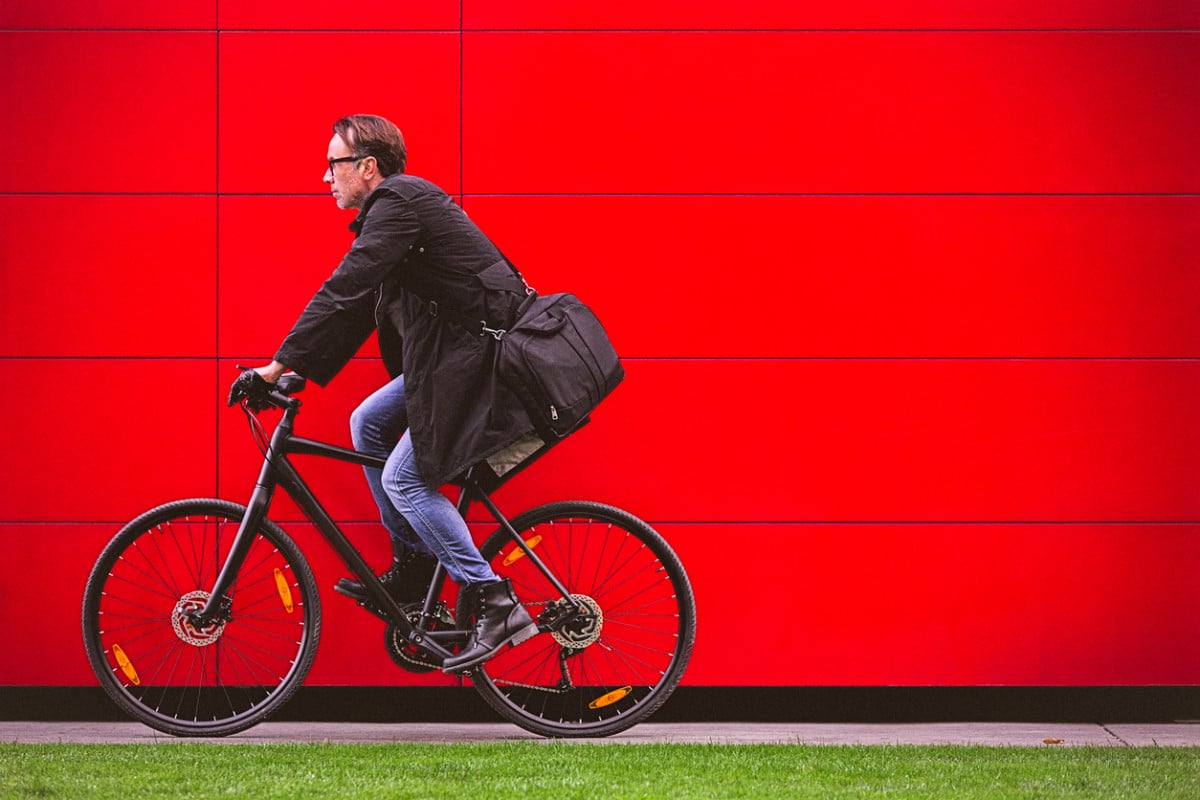 person riding a bike in front of a red wall