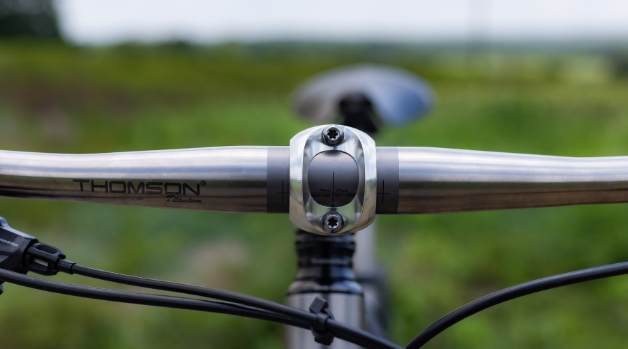 close up image of rider's view of Thomson Ti handlebar with green field behind it